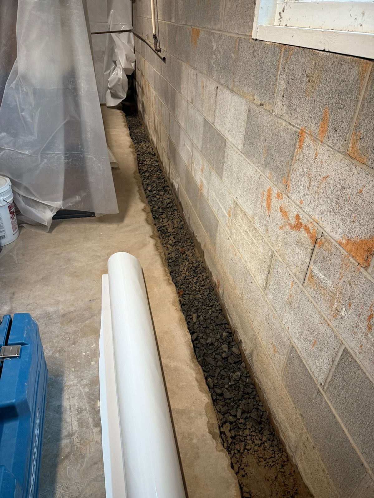 Open interior trench along block wall during French drain installation