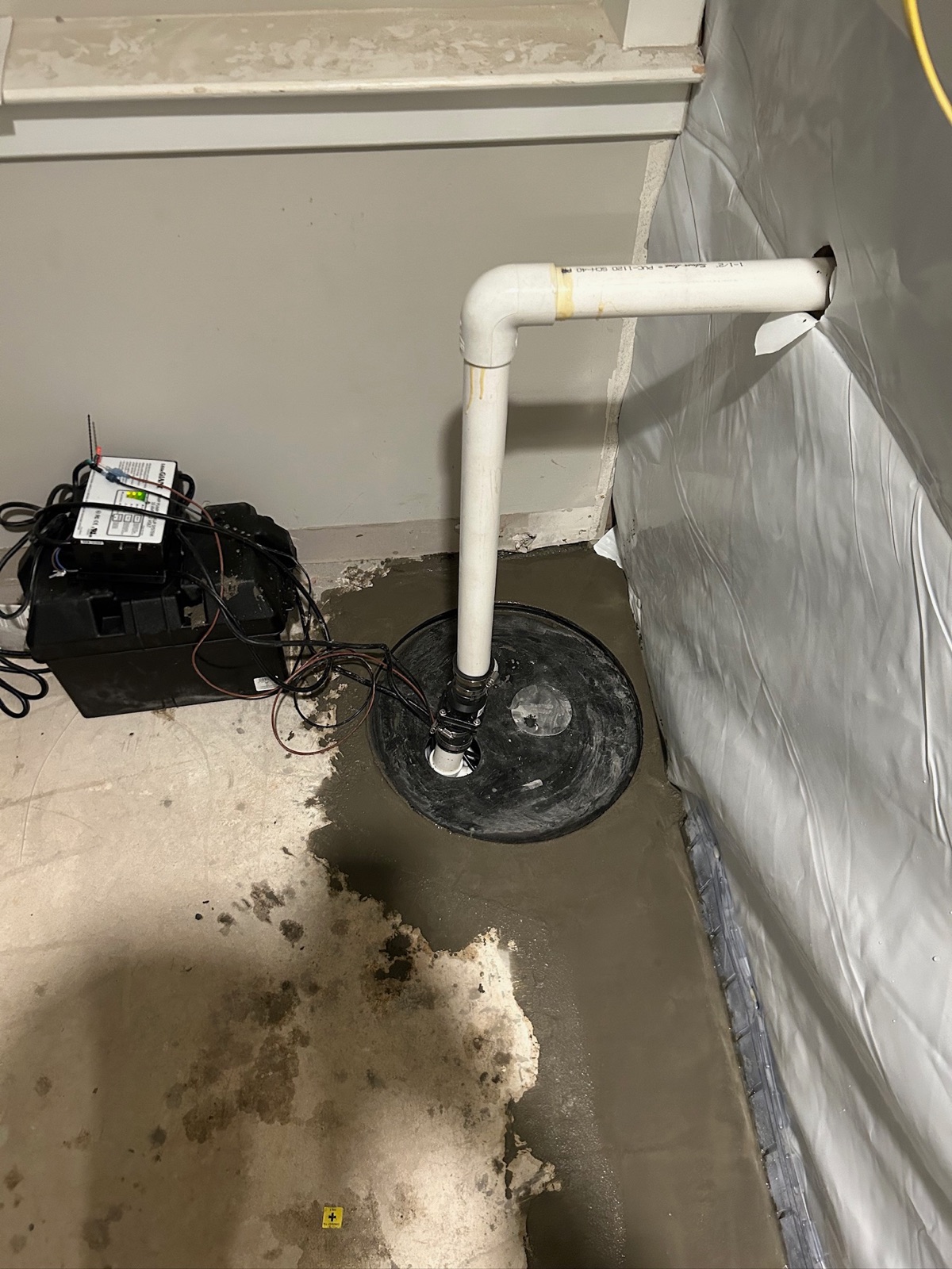 Installed sump pump with battery-backup unit in a finished basement waterproofing system