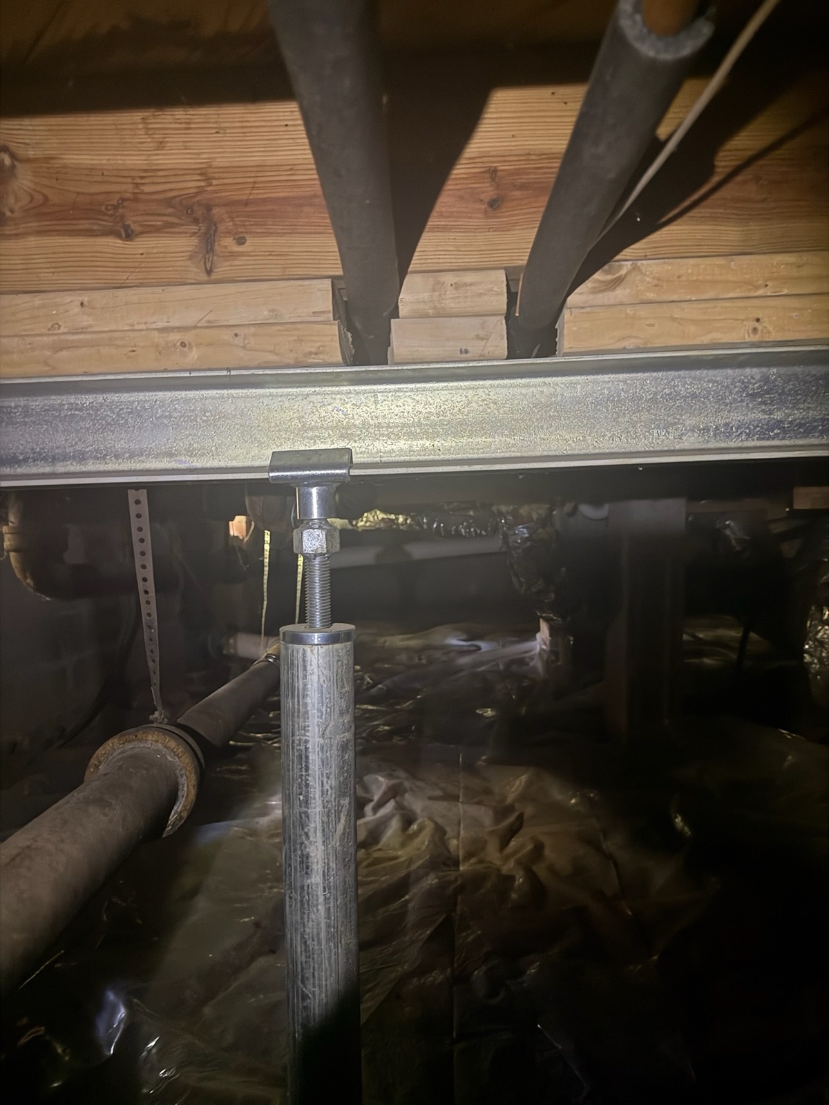 Steel I-beam supported by a SmartJack stabilization column being installed under floor joists