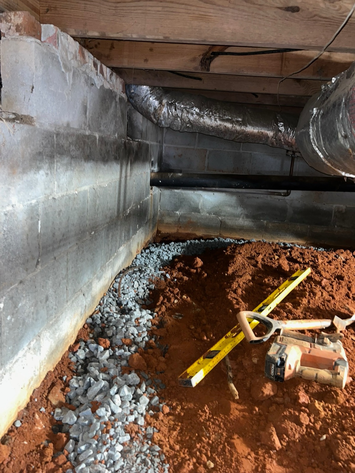 Wide angle of installed gravel drainage trench along block wall — finished interior drainage system